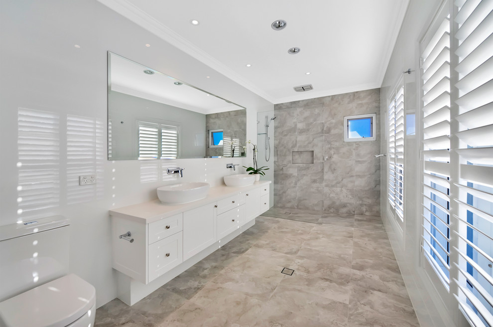 Large contemporary master bathroom in Sydney with recessed-panel cabinets, white cabinets, a freestanding tub, an alcove shower, a one-piece toilet, white tile, porcelain tile, white walls, porcelain floors, a trough sink, engineered quartz benchtops, brown floor, an open shower and white benchtops.