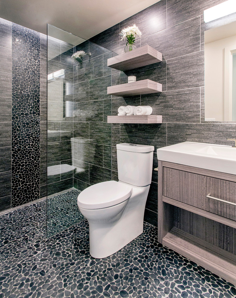 Design ideas for a mid-sized contemporary bathroom in San Diego with flat-panel cabinets, medium wood cabinets, an open shower, black tile, porcelain tile, black walls, pebble tile floors, a trough sink, black floor and an open shower.