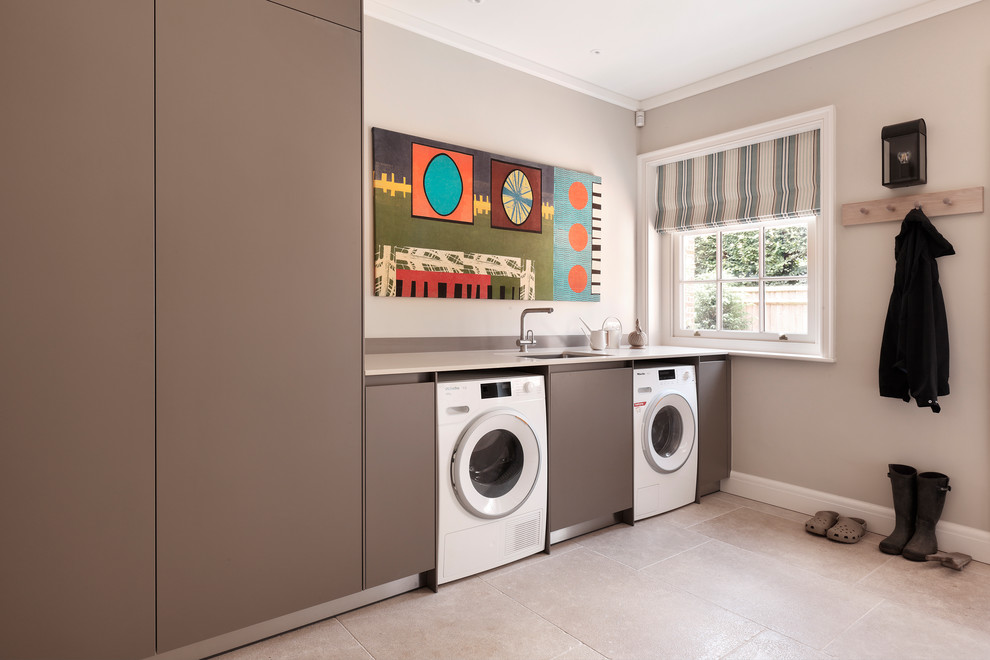 Inspiration for a scandinavian single-wall dedicated laundry room in London with an undermount sink, flat-panel cabinets, grey cabinets, grey walls, a side-by-side washer and dryer, beige floor and white benchtop.