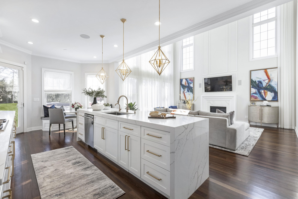 This is an example of a large traditional single-wall open plan kitchen in New York with an undermount sink, shaker cabinets, white cabinets, quartz benchtops, white splashback, engineered quartz splashback, panelled appliances, medium hardwood floors, with island, brown floor and white benchtop.