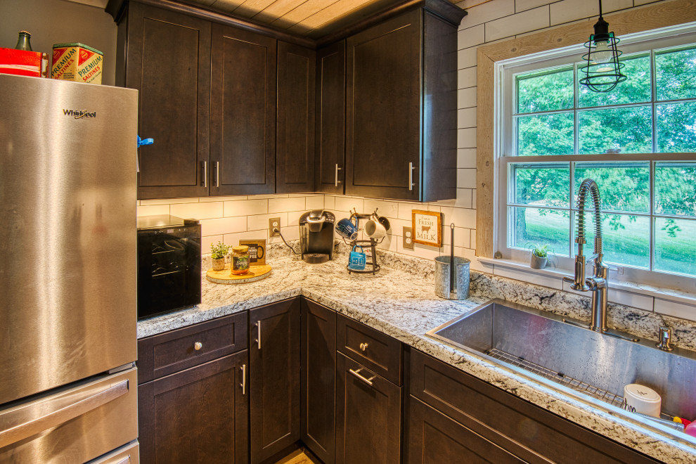 Example of a mid-sized transitional u-shaped light wood floor and brown floor open concept kitchen design with a drop-in sink, shaker cabinets, gray cabinets, laminate countertops, white backsplash, subway tile backsplash, stainless steel appliances, a peninsula and white countertops