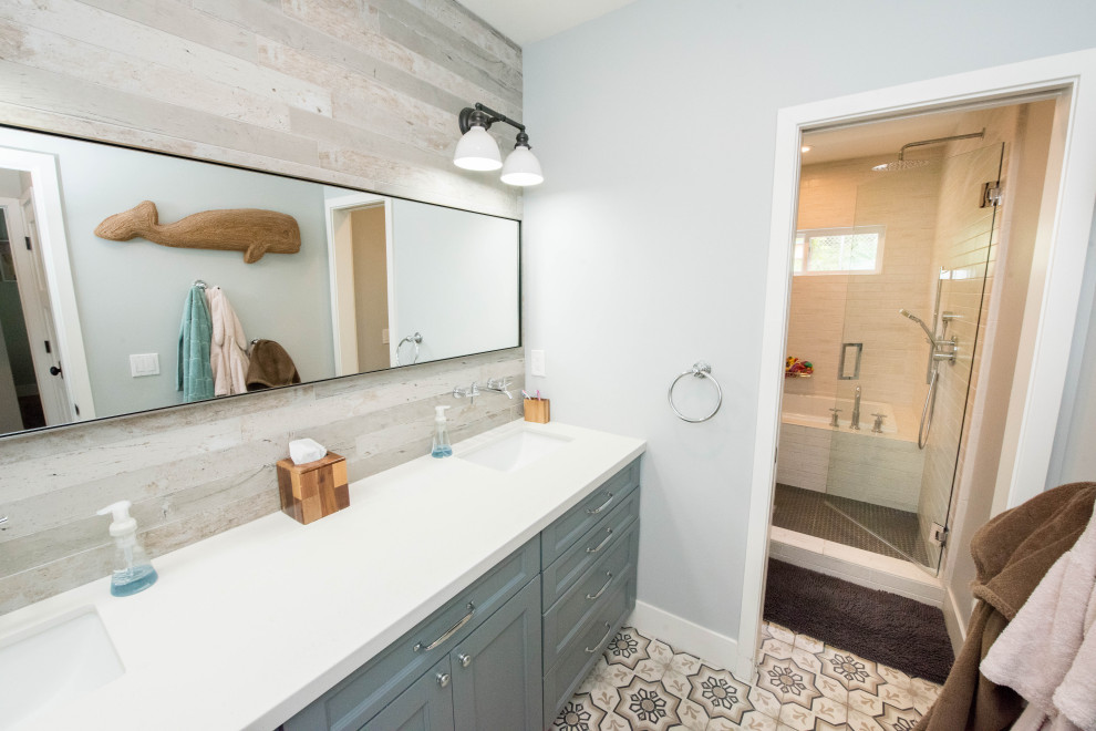 Inspiration for a mid-sized country kids bathroom in San Diego with shaker cabinets, blue cabinets, a drop-in tub, a shower/bathtub combo, gray tile, porcelain tile, blue walls, cement tiles, an undermount sink, engineered quartz benchtops, a hinged shower door, white benchtops, a double vanity and a built-in vanity.