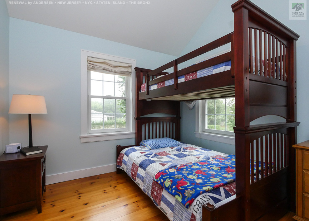 Mittelgroßes, Neutrales Kinderzimmer mit blauer Wandfarbe, braunem Holzboden, gewölbter Decke und Schlafplatz in Newark