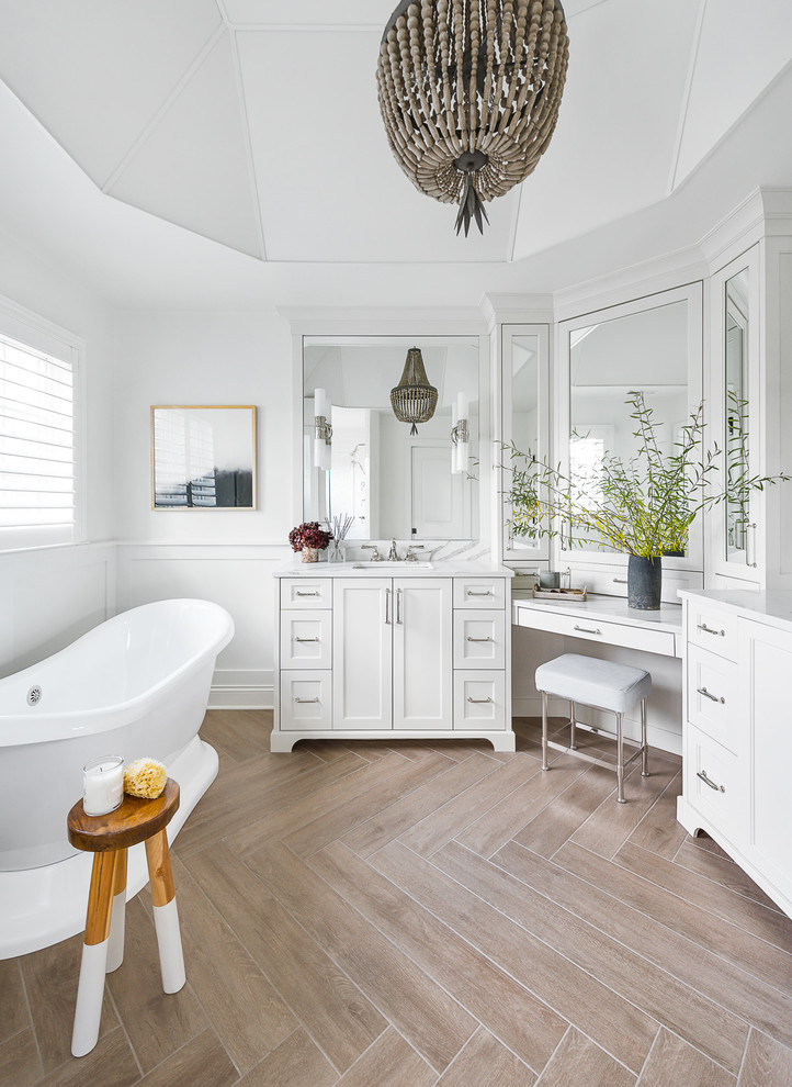 Inspiration for a large transitional master bathroom in Chicago with flat-panel cabinets, white cabinets, a freestanding tub, an alcove shower, a one-piece toilet, white tile, porcelain tile, white walls, porcelain floors, a drop-in sink, engineered quartz benchtops, brown floor, a hinged shower door and white benchtops.