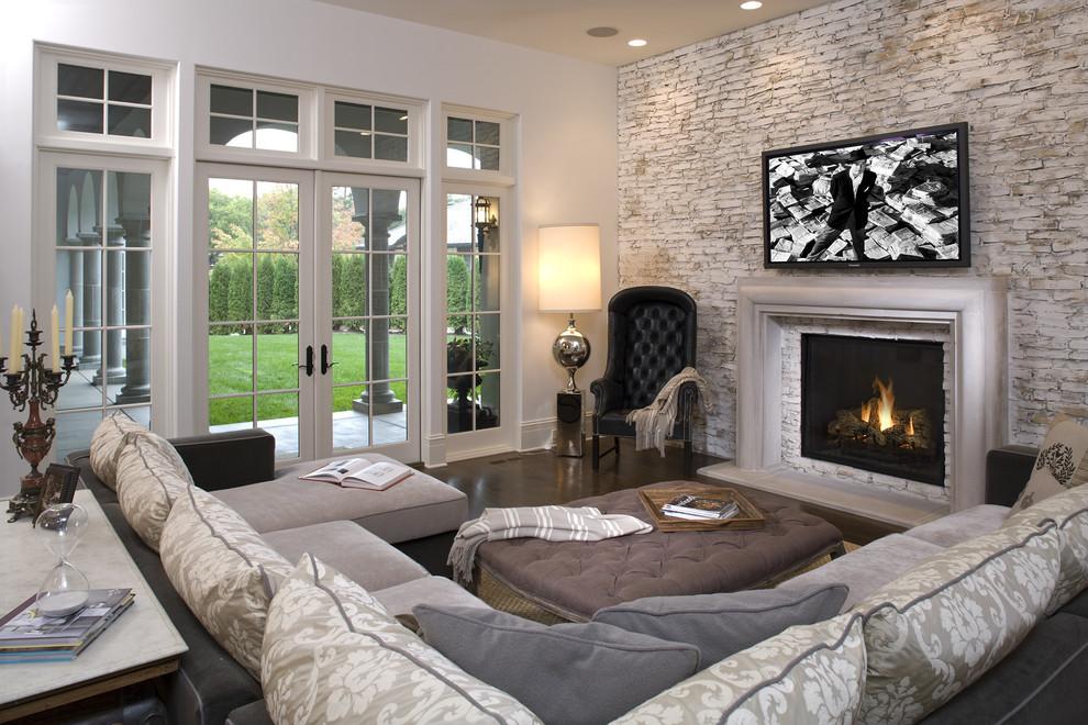 Mediterranean family room in Minneapolis with beige walls, dark hardwood floors, a standard fireplace and a wall-mounted tv.