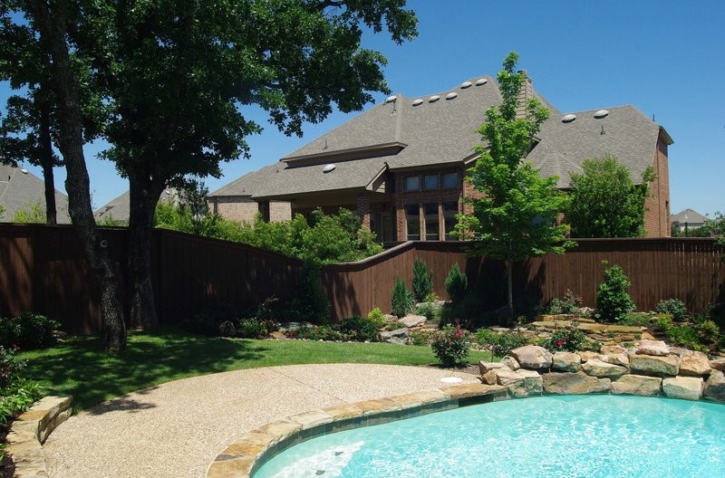 This is an example of a large traditional backyard custom-shaped natural pool in Dallas with concrete pavers.