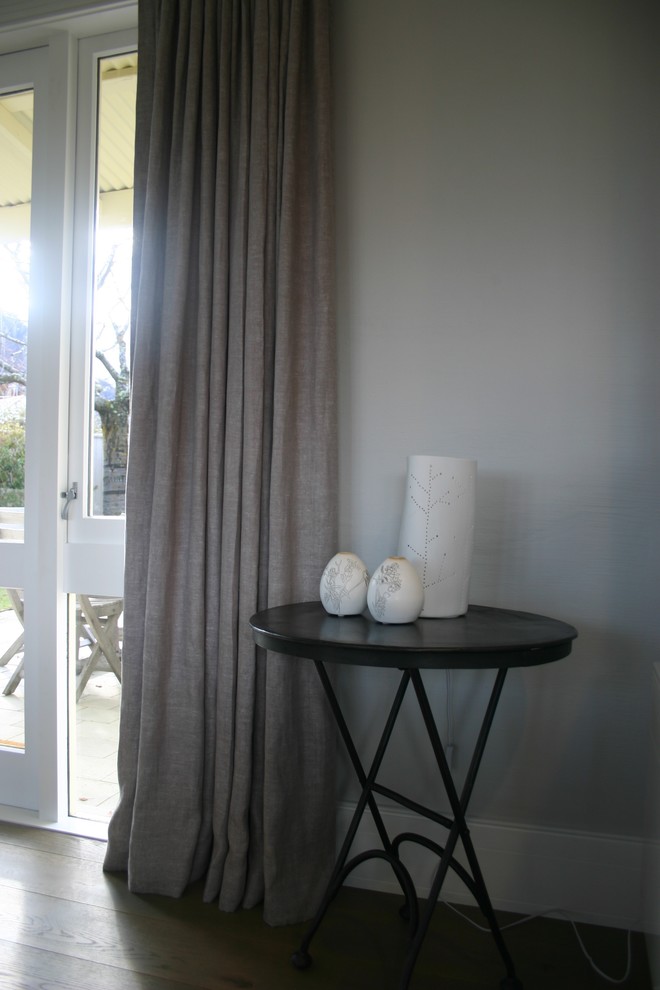 Photo of a Mid-sized contemporary Formal Open Concept living room in Auckland With Grey Walls, Medium Hardwood Floors, a Standard Fireplace, a Plaster Fireplace Surround and a Freestanding TV.