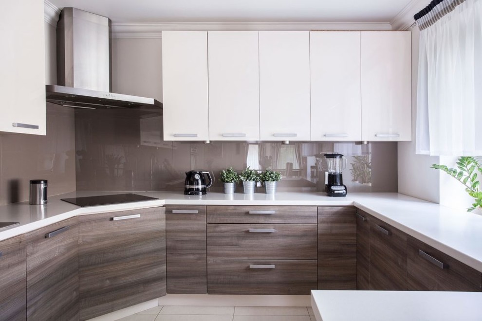 This is an example of a mid-sized contemporary u-shaped kitchen in Los Angeles with flat-panel cabinets, brown splashback, an undermount sink, medium wood cabinets, solid surface benchtops, glass sheet splashback, a peninsula and beige floor.