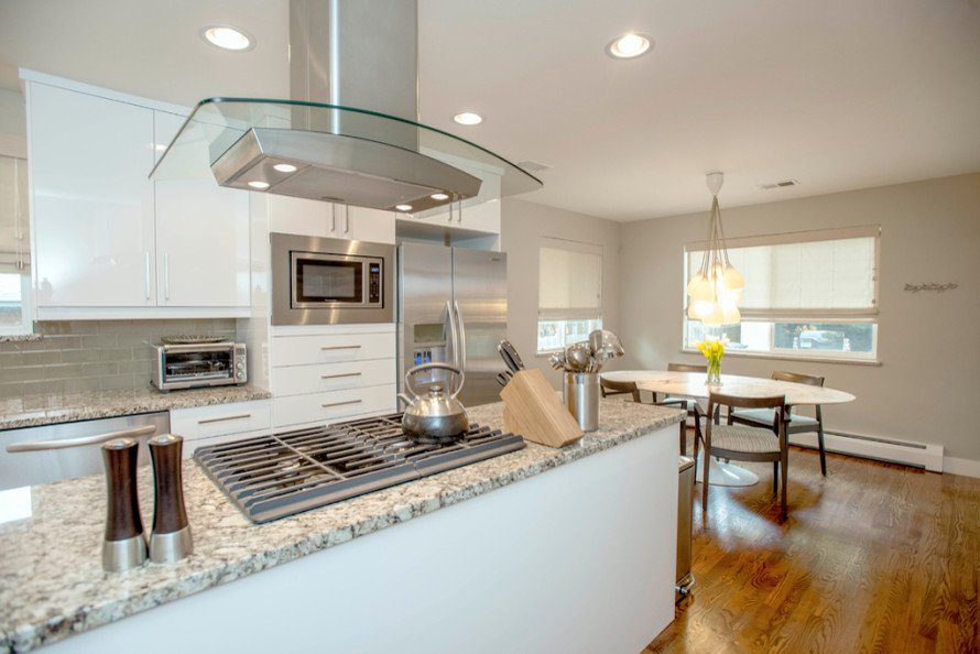 Mid-sized transitional l-shaped light wood floor eat-in kitchen photo in Denver with flat-panel cabinets, white cabinets, granite countertops, beige backsplash, subway tile backsplash, stainless steel appliances and an island