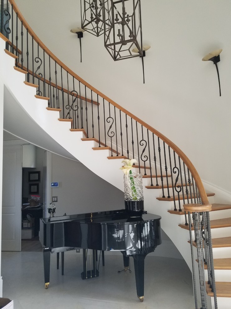 Photo of a mid-sized transitional wood curved staircase in Other with wood risers and mixed railing.