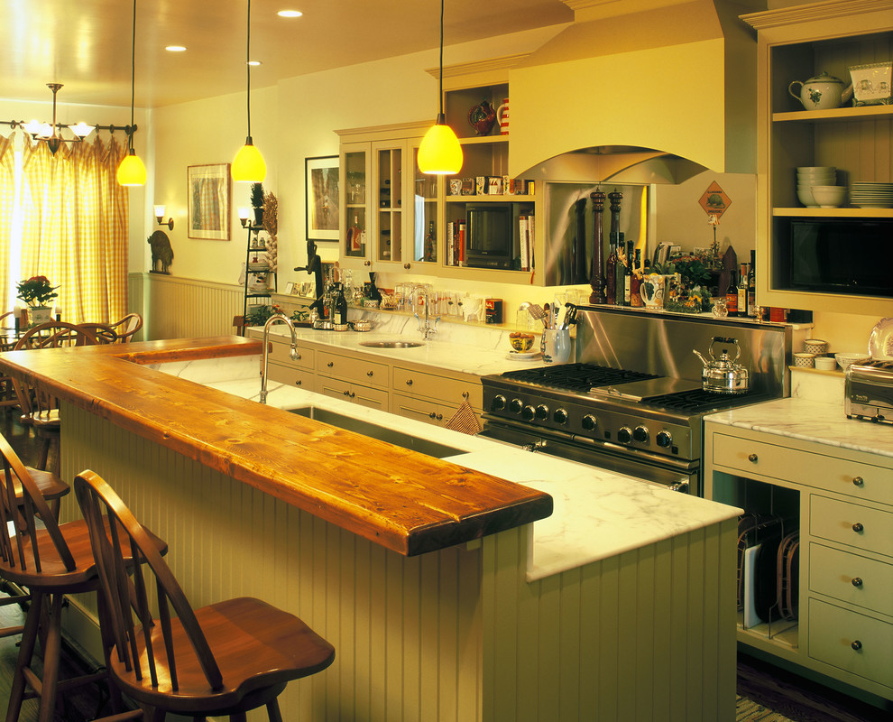 This is an example of a country galley eat-in kitchen in San Francisco with an undermount sink, beaded inset cabinets, yellow cabinets, marble benchtops, white splashback, stone slab splashback and panelled appliances.