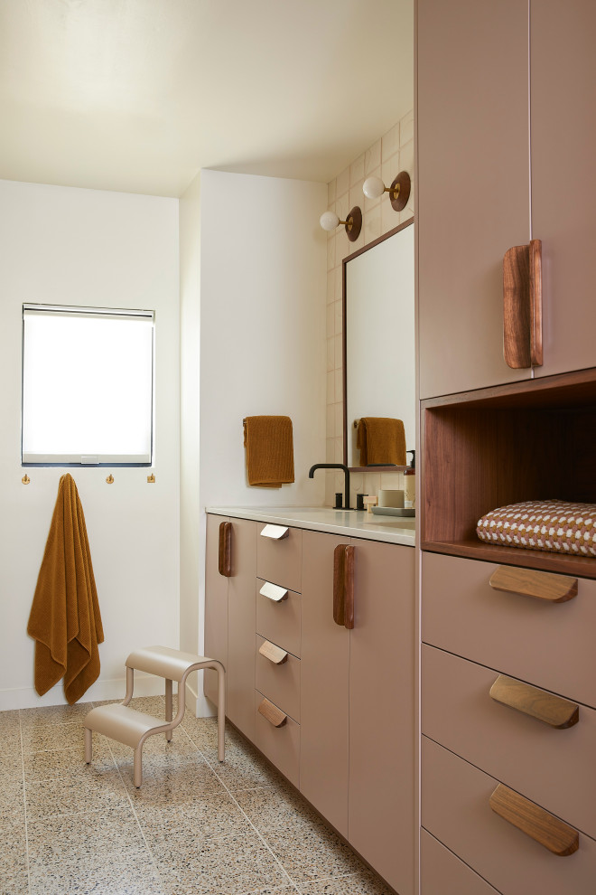 Стильный дизайн: детская ванная комната среднего размера в стиле ретро с плоскими фасадами, коричневыми фасадами, ванной в нише, душем над ванной, унитазом-моноблоком, белой плиткой, керамической плиткой, белыми стенами, полом из терраццо, врезной раковиной, столешницей из искусственного кварца, коричневым полом, шторкой для ванной, серой столешницей, нишей, тумбой под две раковины и встроенной тумбой - последний тренд