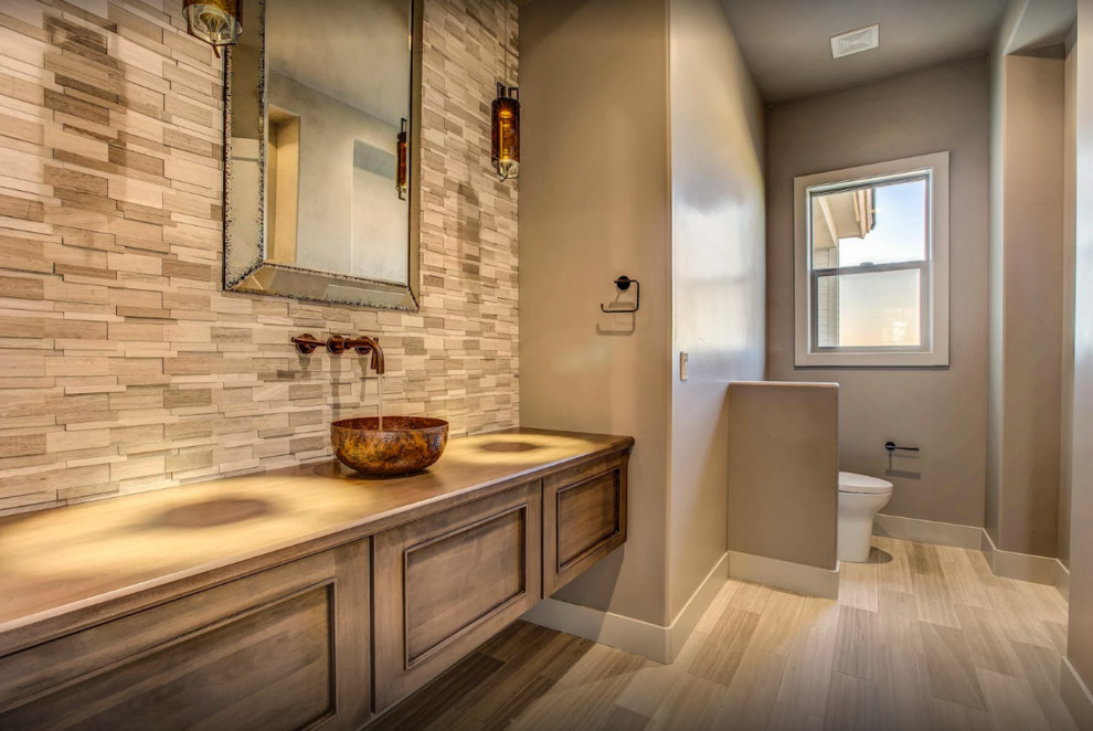 Example of a mid-sized transitional 3/4 porcelain tile and beige floor bathroom design with recessed-panel cabinets, medium tone wood cabinets, a two-piece toilet, gray walls, a vessel sink and wood countertops