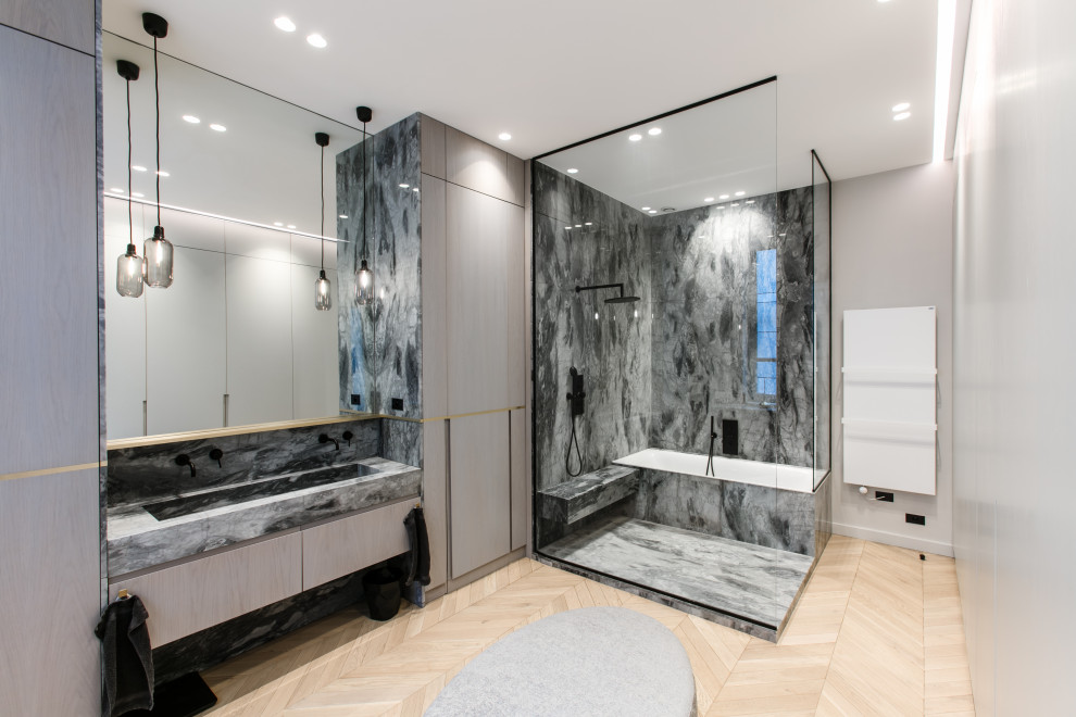 This is an example of a contemporary master wet room bathroom in Paris with flat-panel cabinets, a drop-in tub, multi-coloured tile, stone slab, light hardwood floors, a trough sink and multi-coloured benchtops.