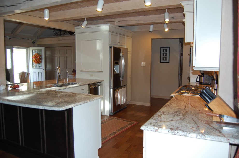Inspiration for a mid-sized transitional u-shaped medium tone wood floor open concept kitchen remodel in Chicago with an undermount sink, flat-panel cabinets, dark wood cabinets, granite countertops, beige backsplash, stone tile backsplash, stainless steel appliances and a peninsula