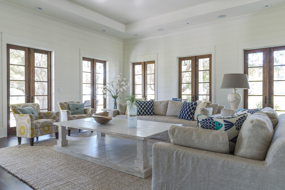 Beach style living room in New Orleans with white walls, dark hardwood floors and brown floor.