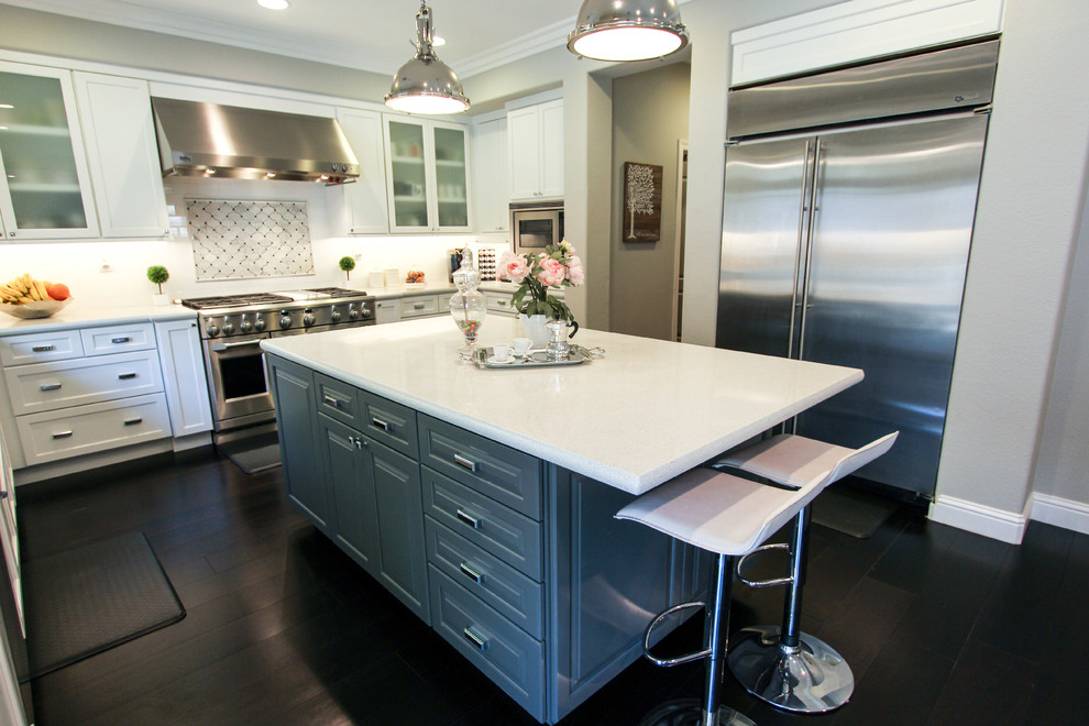 This is an example of a large transitional u-shaped open plan kitchen in San Francisco with a farmhouse sink, recessed-panel cabinets, white cabinets, quartz benchtops, white splashback, porcelain splashback, stainless steel appliances, dark hardwood floors and with island.