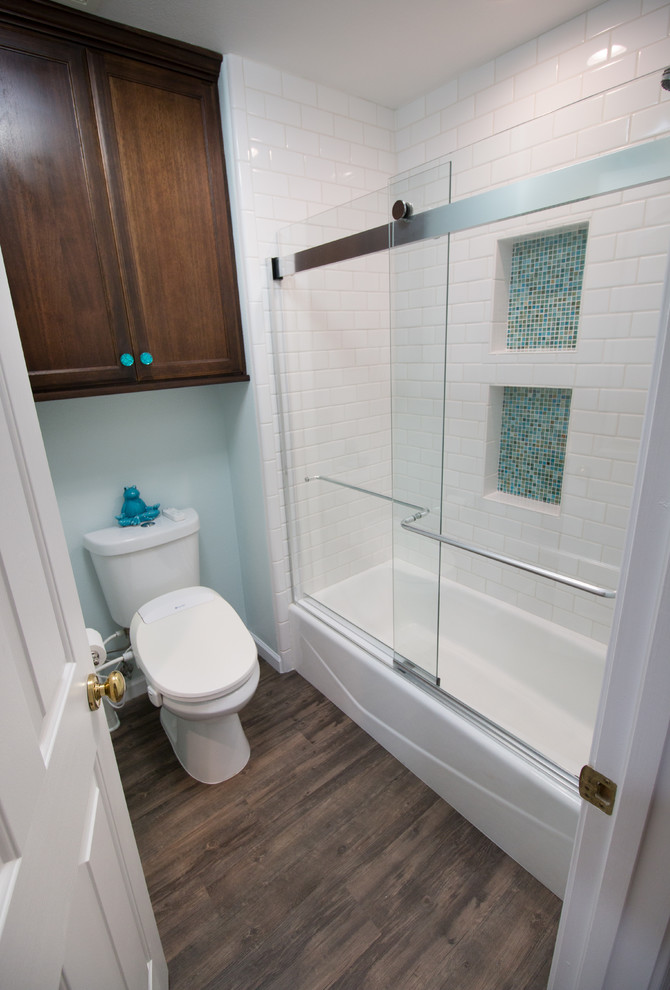 Design ideas for a small eclectic kids bathroom in Other with recessed-panel cabinets, dark wood cabinets, an alcove tub, a two-piece toilet, blue tile, subway tile, blue walls, vinyl floors, an undermount sink, engineered quartz benchtops and brown floor.