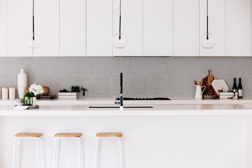 Contemporary galley kitchen in Melbourne with an undermount sink, flat-panel cabinets, white cabinets, white splashback, mosaic tile splashback, with island and white benchtop.