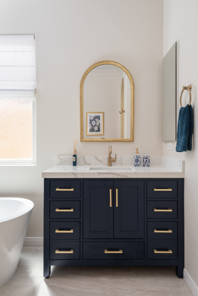 Design ideas for a large transitional master bathroom in San Diego with recessed-panel cabinets, blue cabinets, a freestanding tub, beige tile, beige walls, porcelain floors, an undermount sink, marble benchtops, beige floor, white benchtops, a niche, a double vanity and a built-in vanity.