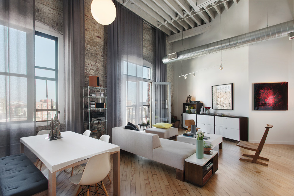 Large modern loft-style living room in Philadelphia with white walls, light hardwood floors, no fireplace and brown floor.