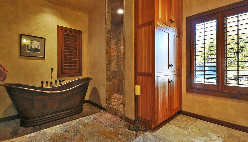 Inspiration for a country bathroom in Austin with an undermount sink, raised-panel cabinets, medium wood cabinets, marble benchtops, a freestanding tub, an open shower, beige tile and stone slab.