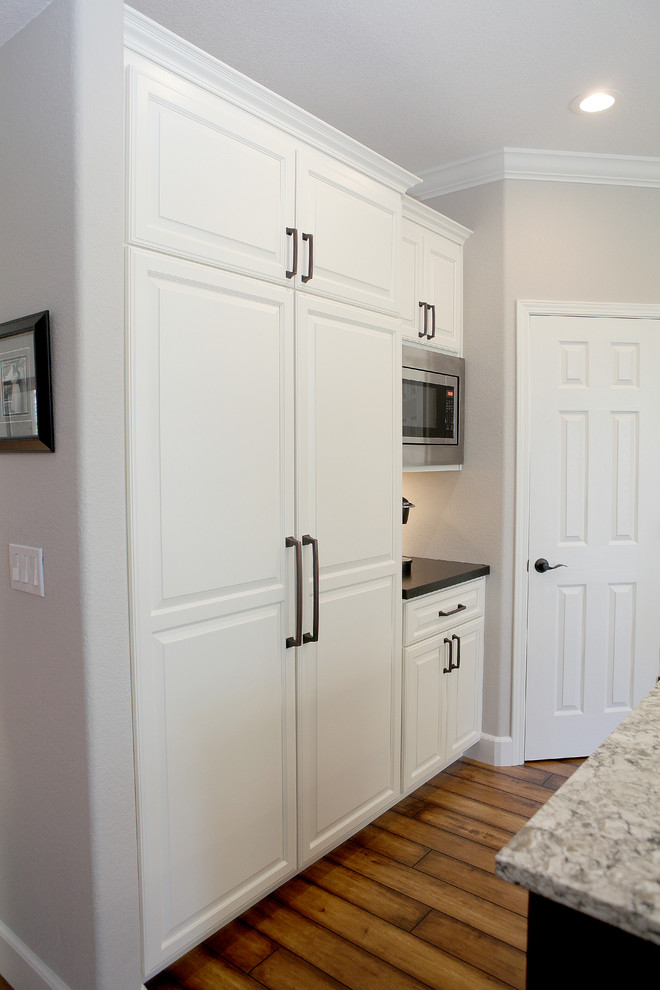 Inspiration for a transitional eat-in kitchen remodel in Sacramento with a single-bowl sink, white cabinets, solid surface countertops and stainless steel appliances