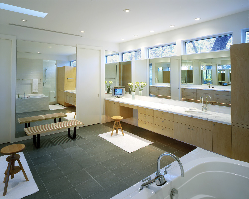 Inspiration for a large modern master bathroom in Portland with flat-panel cabinets, light wood cabinets, a drop-in tub, an alcove shower, a one-piece toilet, white tile, ceramic tile, white walls, limestone floors, an undermount sink and marble benchtops.