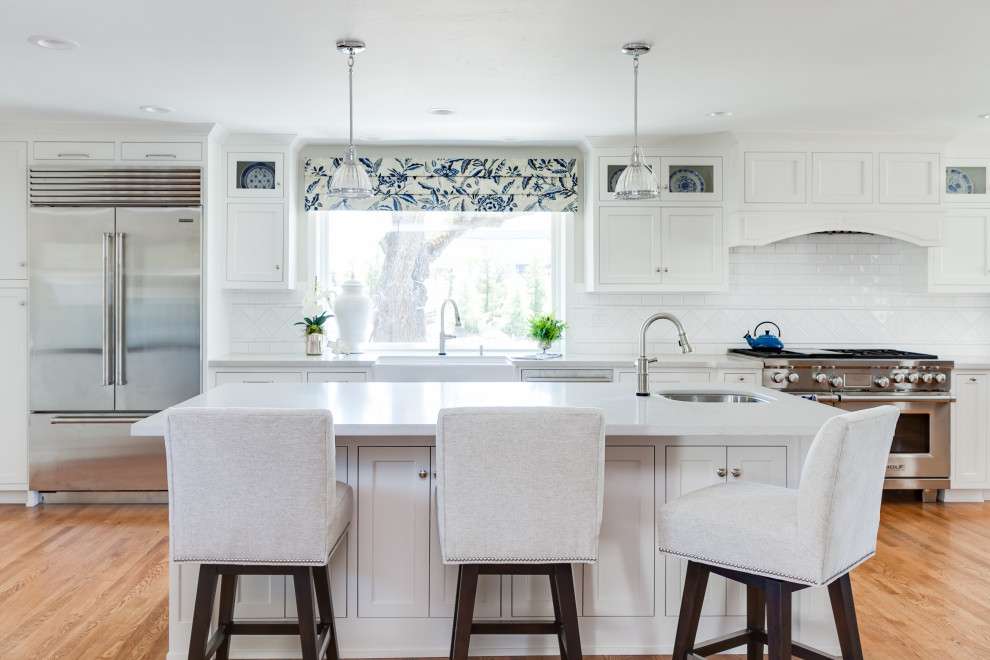 Mid-sized traditional single-wall eat-in kitchen in Sacramento with a farmhouse sink, beaded inset cabinets, white cabinets, quartz benchtops, white splashback, ceramic splashback, stainless steel appliances, medium hardwood floors, with island, yellow floor and white benchtop.