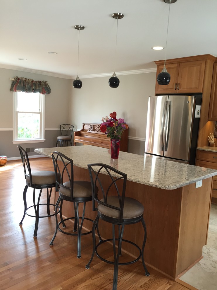 Inspiration for a mid-sized transitional medium tone wood floor kitchen remodel in DC Metro with raised-panel cabinets, medium tone wood cabinets, stainless steel appliances and an island