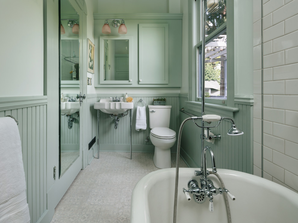 Photo of a traditional bathroom in Portland with a claw-foot tub, a two-piece toilet, white tile, ceramic tile, green walls, vinyl floors, a console sink and grey floor.