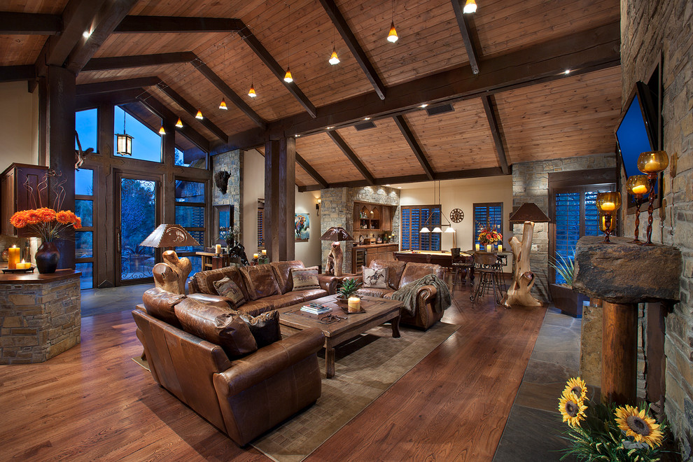 Mid-sized country open concept living room in Phoenix with beige walls, medium hardwood floors, a stone fireplace surround and a wall-mounted tv.