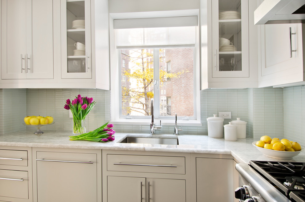 Enclosed kitchen - traditional u-shaped dark wood floor enclosed kitchen idea in Miami with flat-panel cabinets, gray cabinets, quartzite countertops, blue backsplash, glass tile backsplash, stainless steel appliances and an undermount sink