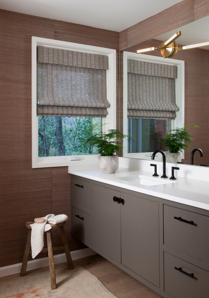 Photo of a contemporary powder room in Austin with flat-panel cabinets, grey cabinets, brown walls, medium hardwood floors, an undermount sink, brown floor and white benchtops.