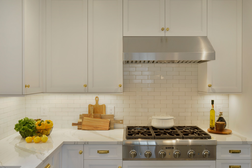 Example of a small transitional u-shaped porcelain tile and gray floor enclosed kitchen design in New York with an undermount sink, recessed-panel cabinets, white cabinets, quartz countertops, white backsplash, ceramic backsplash, stainless steel appliances, an island and white countertops