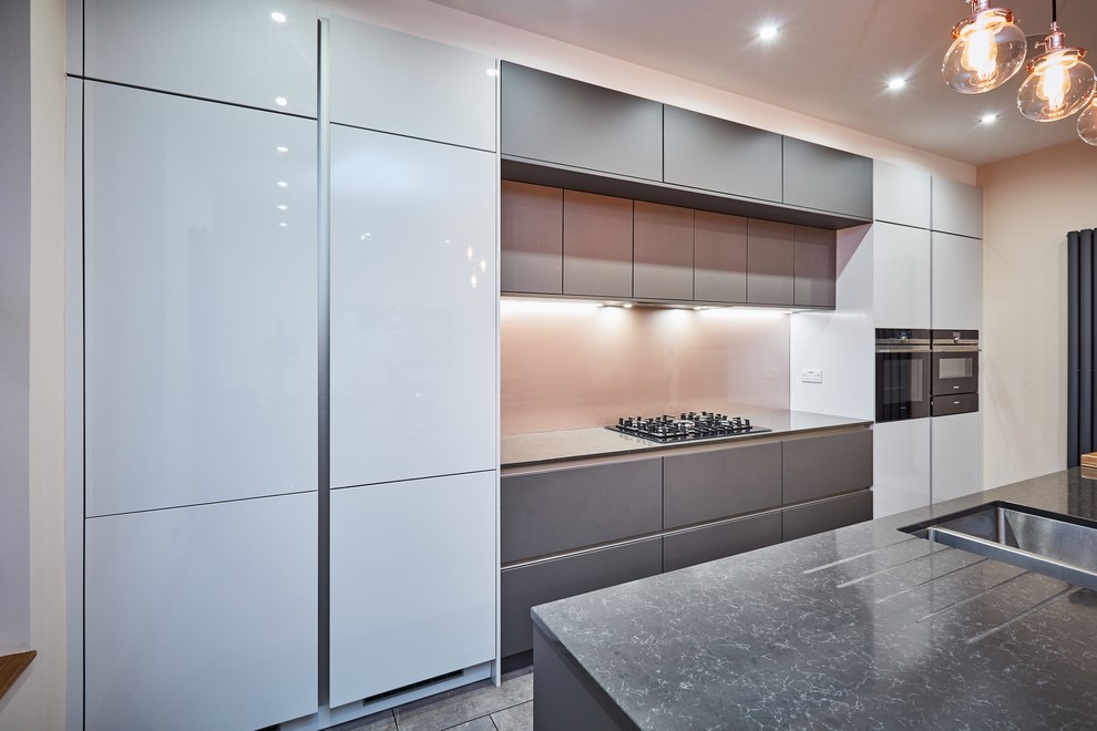 Photo of a mid-sized modern single-wall eat-in kitchen in Other with a drop-in sink, flat-panel cabinets, grey cabinets, quartzite benchtops, metallic splashback, glass sheet splashback, stainless steel appliances, ceramic floors, with island, grey floor and grey benchtop.