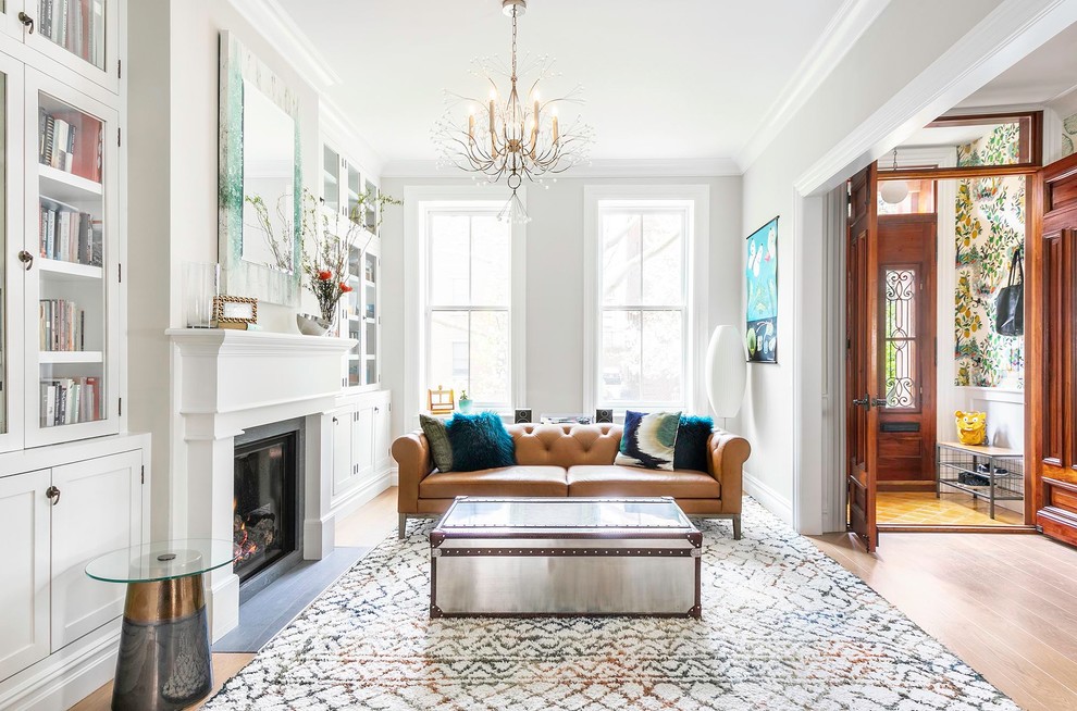 Photo of a transitional open concept living room in New York with white walls, medium hardwood floors, a standard fireplace and brown floor.