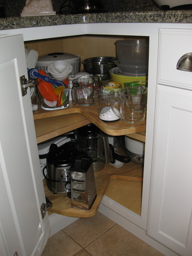 Example of a transitional l-shaped ceramic tile and beige floor kitchen design in Boston with an undermount sink, shaker cabinets, white cabinets, granite countertops, white appliances and green countertops