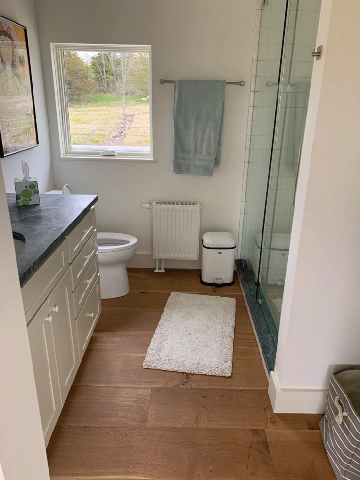 Immagine di una stanza da bagno stile shabby con pavimento in legno massello medio, lavabo sottopiano, porta doccia scorrevole e un lavabo