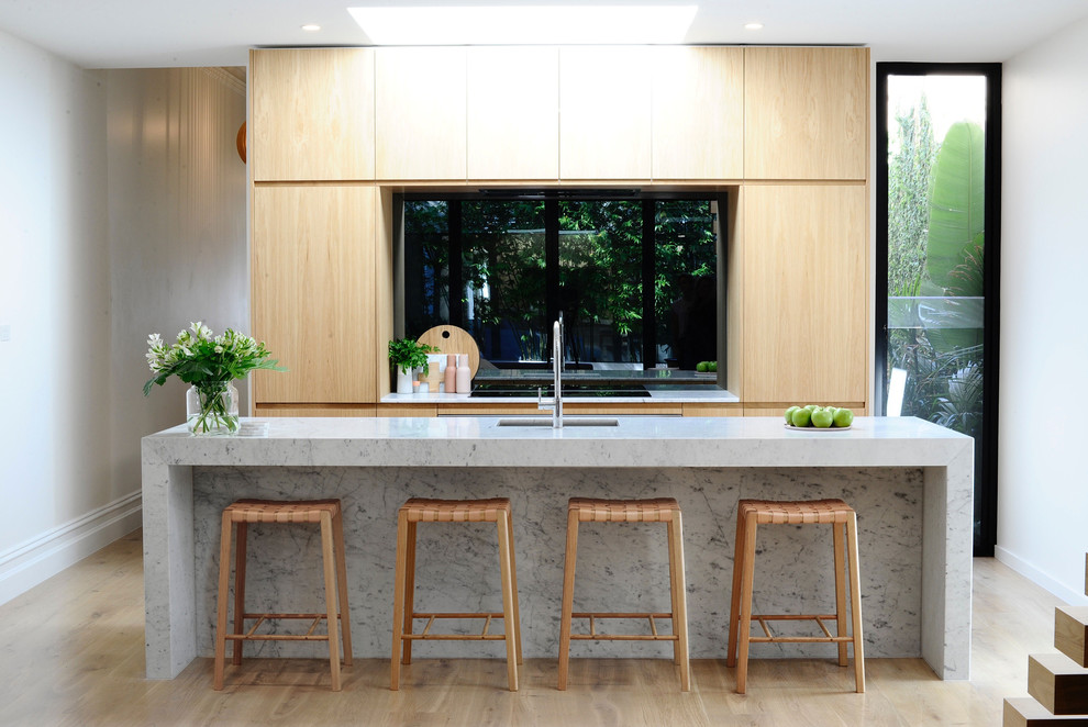 This is an example of a contemporary galley kitchen in Melbourne with an undermount sink, flat-panel cabinets, light wood cabinets, window splashback, stainless steel appliances and with island.