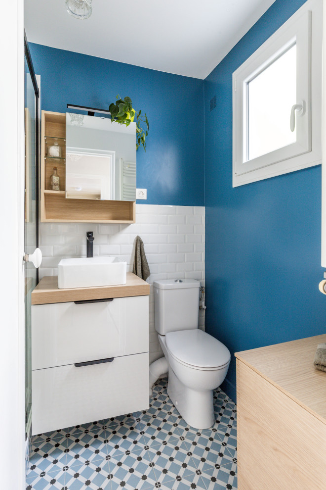 Cette photo montre une petite salle de bain principale tendance en bois clair avec un placard à porte affleurante, une douche ouverte, WC à poser, un carrelage blanc, un carrelage métro, un mur bleu, carreaux de ciment au sol, un plan vasque, un plan de toilette en bois, un sol bleu, une cabine de douche à porte coulissante, un plan de toilette beige, une niche, meuble simple vasque et meuble-lavabo suspendu.