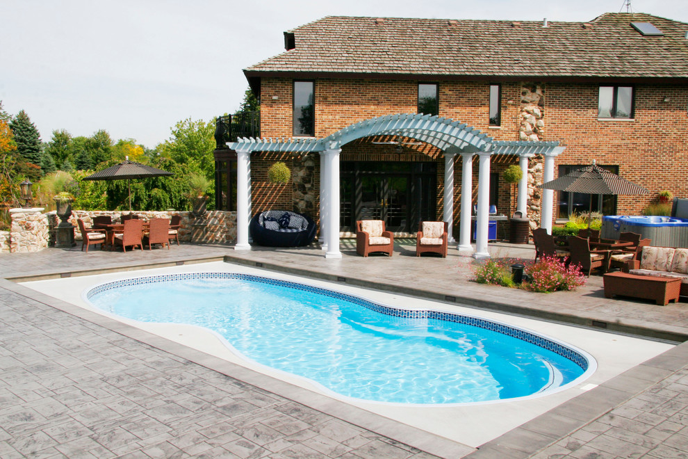Inspiration for a mid-sized timeless backyard concrete paver and custom-shaped hot tub remodel