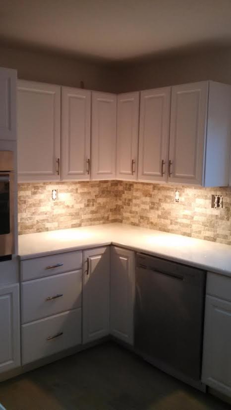 Mid-sized transitional l-shaped porcelain tile enclosed kitchen photo in Austin with beige backsplash, stone tile backsplash, stainless steel appliances, raised-panel cabinets, white cabinets, quartz countertops and no island