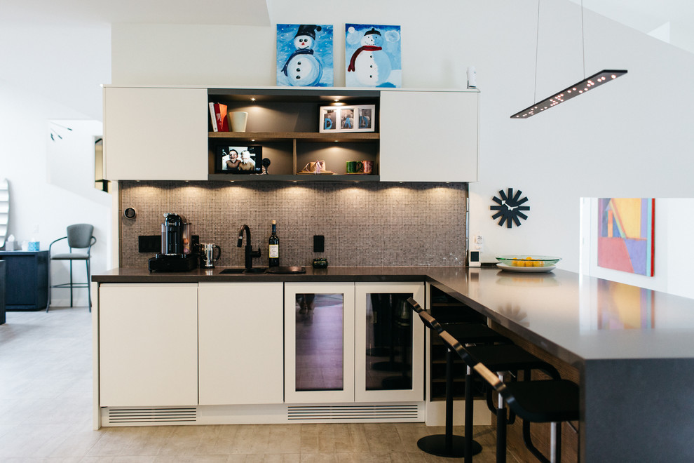 Inspiration for a mid-sized modern u-shaped open plan kitchen in Salt Lake City with flat-panel cabinets, white cabinets, zinc benchtops, black appliances, ceramic floors, with island, a double-bowl sink, brown splashback and mosaic tile splashback.