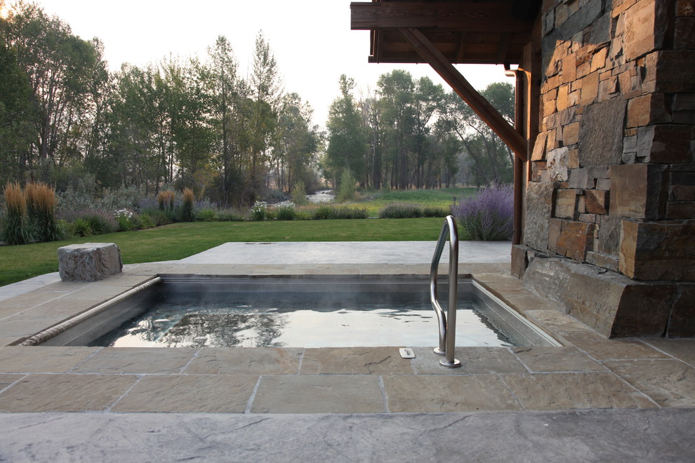 Inspiration for a country pool in Other with a hot tub and natural stone pavers.