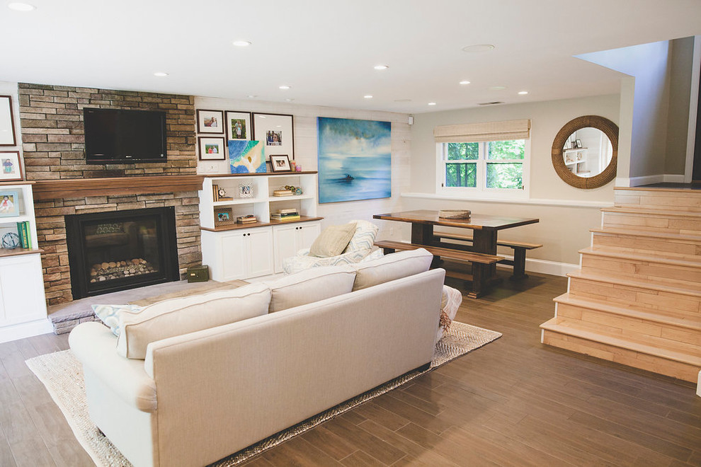 Photo of a mid-sized beach style open concept family room in Providence with a home bar, white walls, porcelain floors, a standard fireplace, a stone fireplace surround, a wall-mounted tv and brown floor.