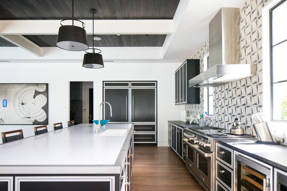 This is an example of a contemporary galley open plan kitchen in Orange County with an undermount sink, recessed-panel cabinets, black cabinets, multi-coloured splashback, stainless steel appliances, medium hardwood floors, with island and brown floor.