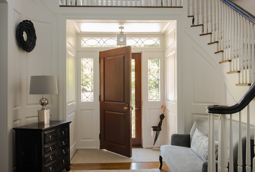 Large traditional foyer in New York with white walls, light hardwood floors, a single front door and a dark wood front door.