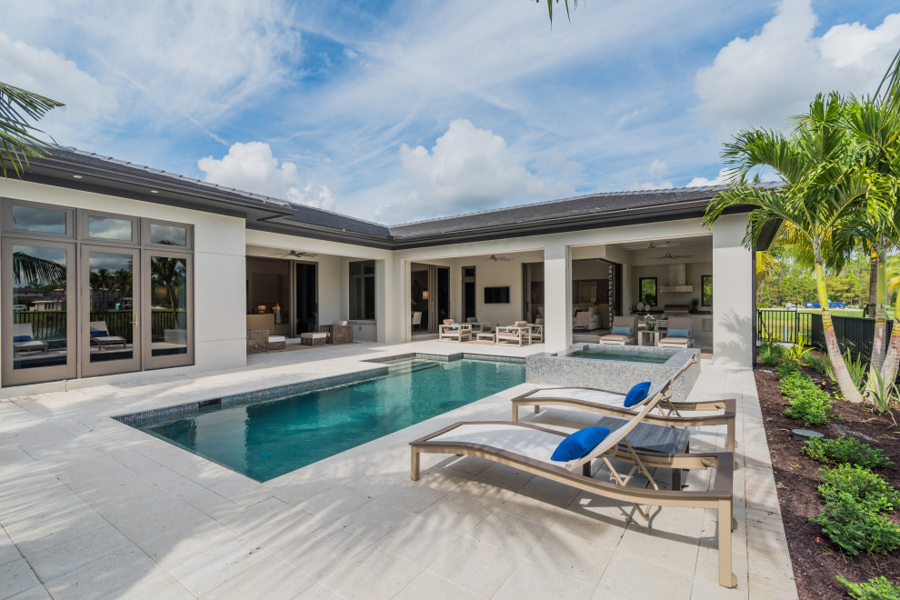 Large mediterranean backyard rectangular pool in Miami with a hot tub and concrete pavers.