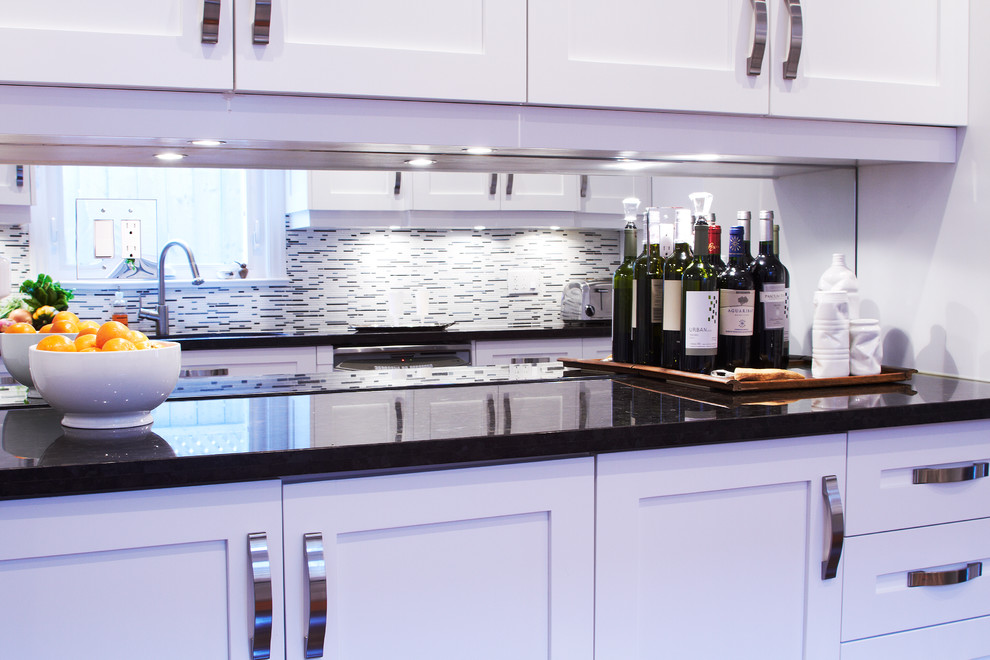 Mid-sized transitional galley dark wood floor enclosed kitchen photo in Toronto with shaker cabinets, white cabinets, granite countertops, stainless steel appliances, multicolored backsplash, a double-bowl sink and matchstick tile backsplash